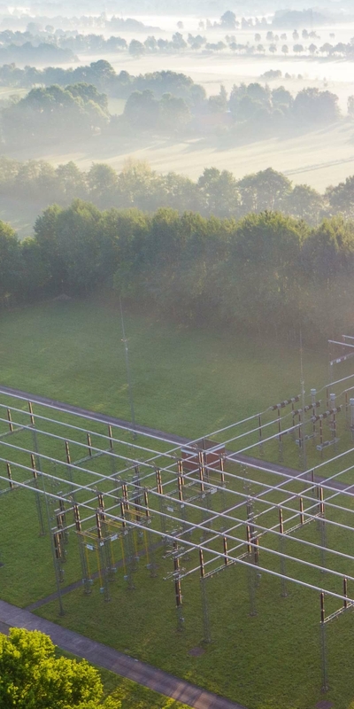 Luftaufnahme eines Umspannwerks in der Natur vor einem Sonnenaufgang