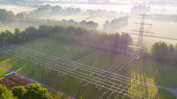 Luftaufnahme eines Umspannwerks in der Natur vor einem Sonnenaufgang
